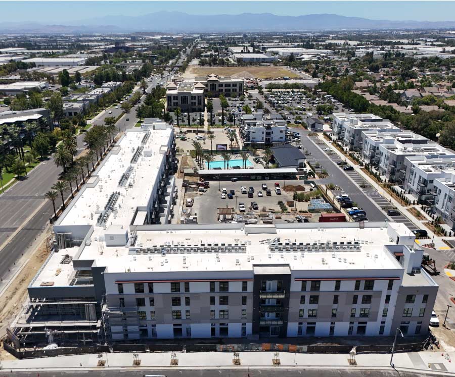 Aerial view of a multi-family residential development with landscaped courtyards, pool and mountain backdrop, representative of NGC Construction Inc.'s multi-family construction projects