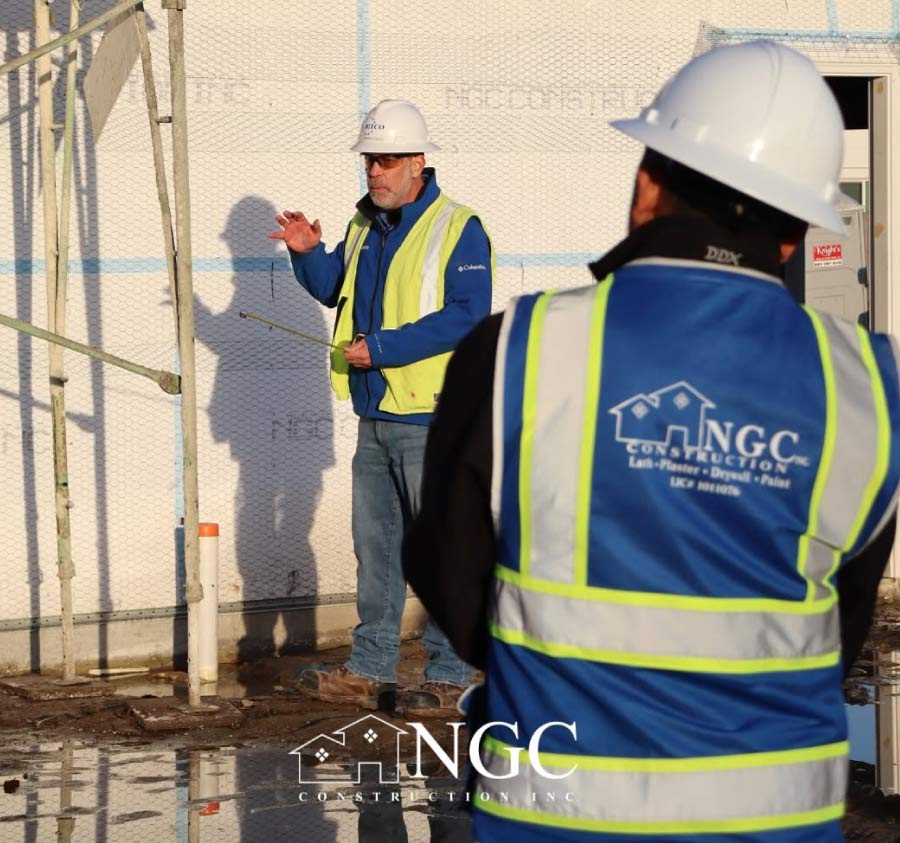 NGC Construction supervisor briefing a crew member on-site during a stucco and drywall project