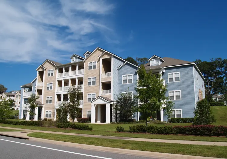 Completed multi-family apartment building with siding exterior, balconies and landscaped grounds